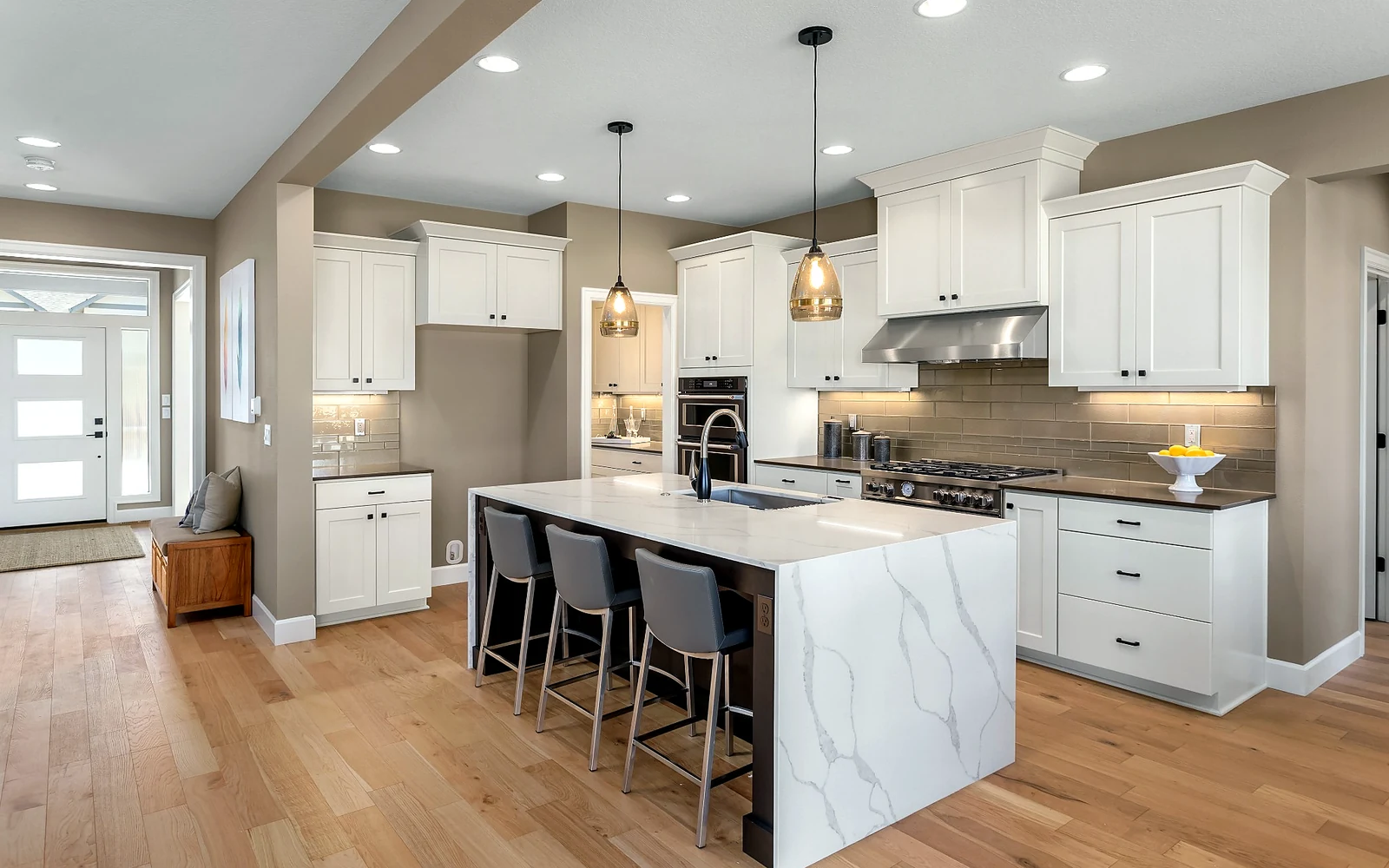 Open kitchen layout with wide walkways, island seating, layered lighting, and durable wood flooring for safer long-term use