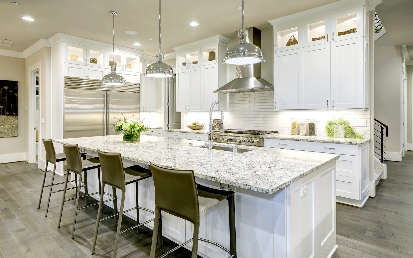 Layered kitchen lighting with island pendants, under cabinet lighting, and bright countertop work zones