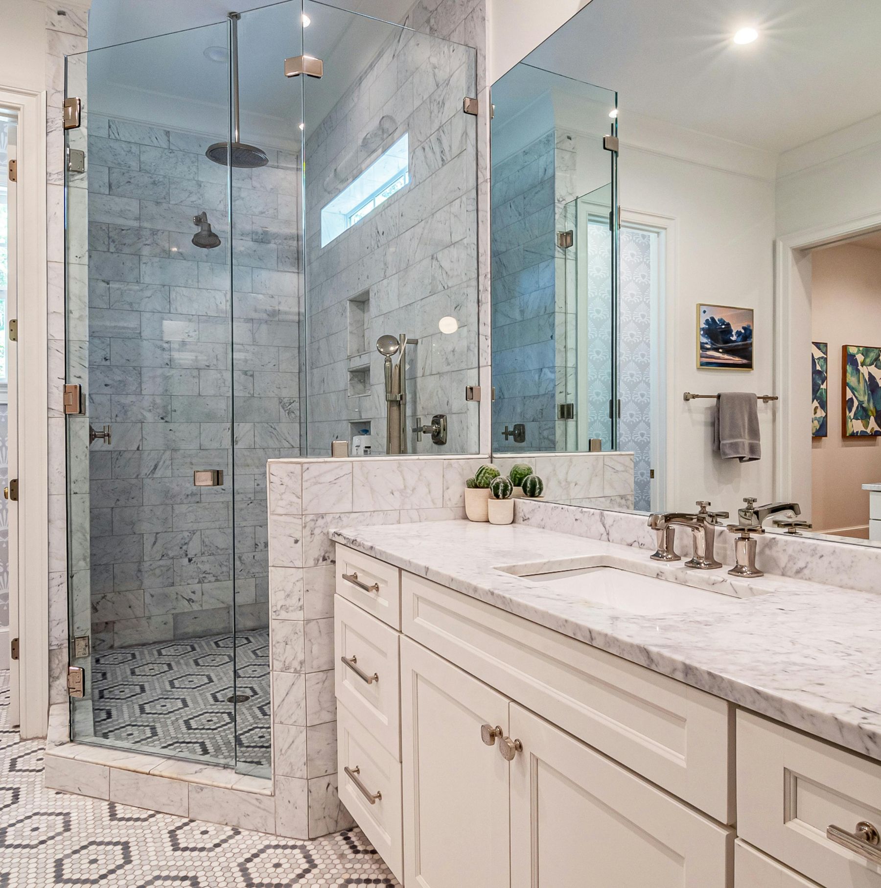 Luxury bathroom with no-curb shower, glass doors, bench, and warm finishes