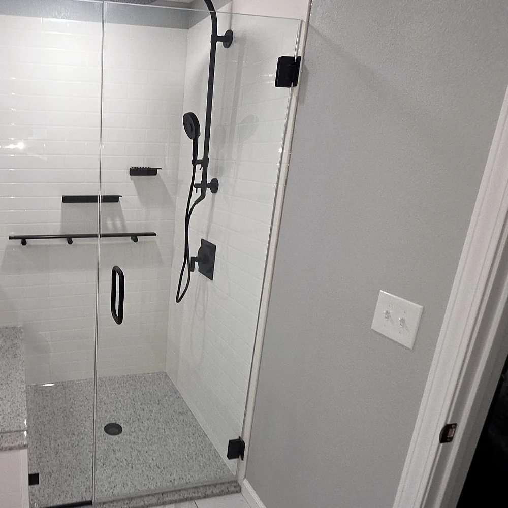 Walk-in glass shower with matte black fixtures and built-in bench